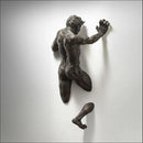 Escultura decorativa de parede em resina com acabamento cobre representando um homem escalando em efeito 3D.