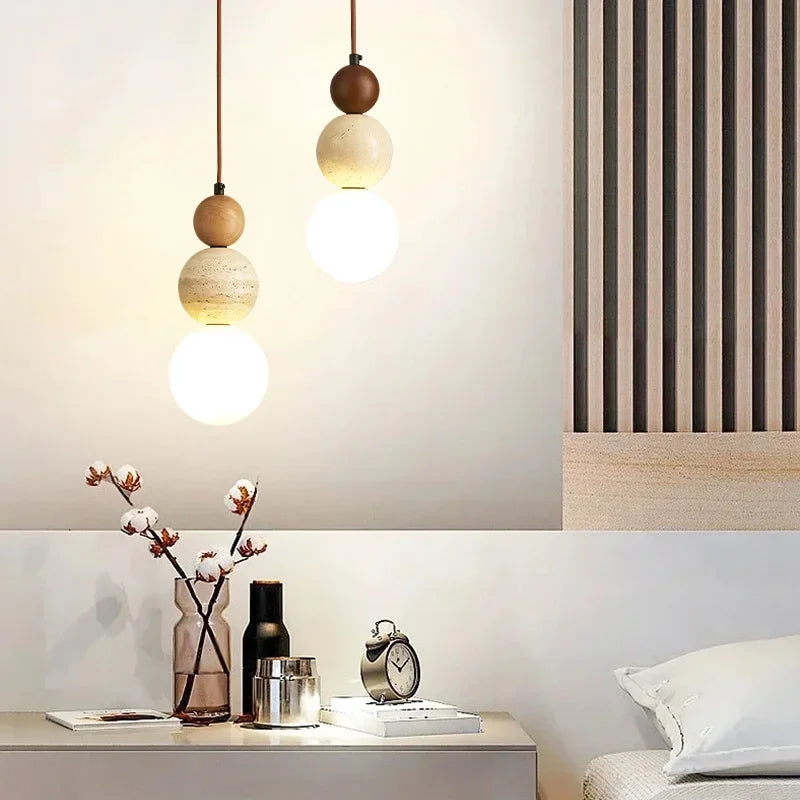 Luminária pendente LED estilo Bauhaus em acabamento creme com detalhes em pedra e madeira instalada sobre uma mesa de cabeceira em um quarto moderno.